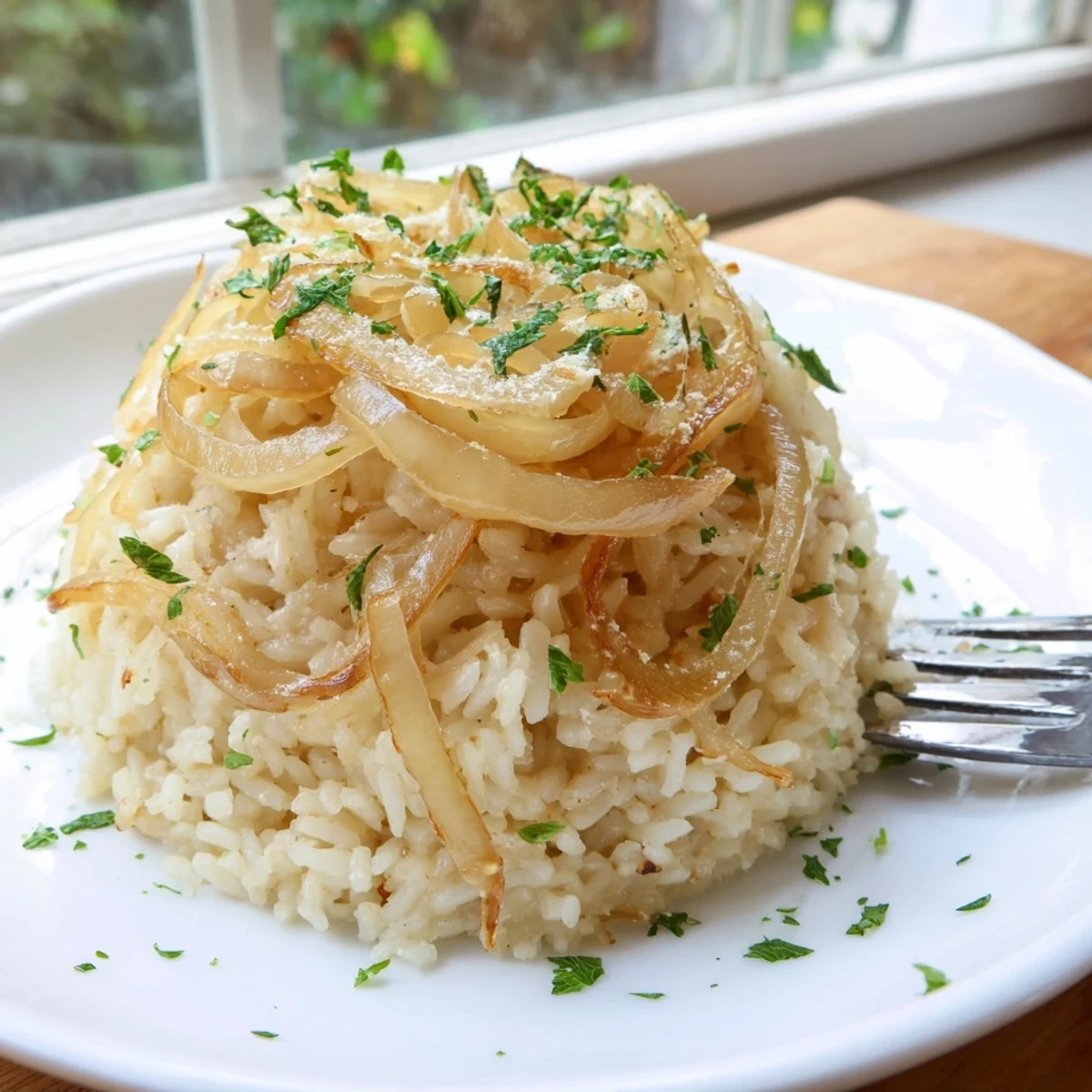Fluffy rice dish with deeply browned onions and melted butter on a rustic wooden serving board