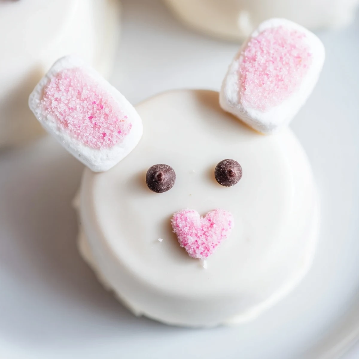 White chocolate Bunny Oreo Balls decorated with marshmallow ears and pink sugar sprinkles on a platter