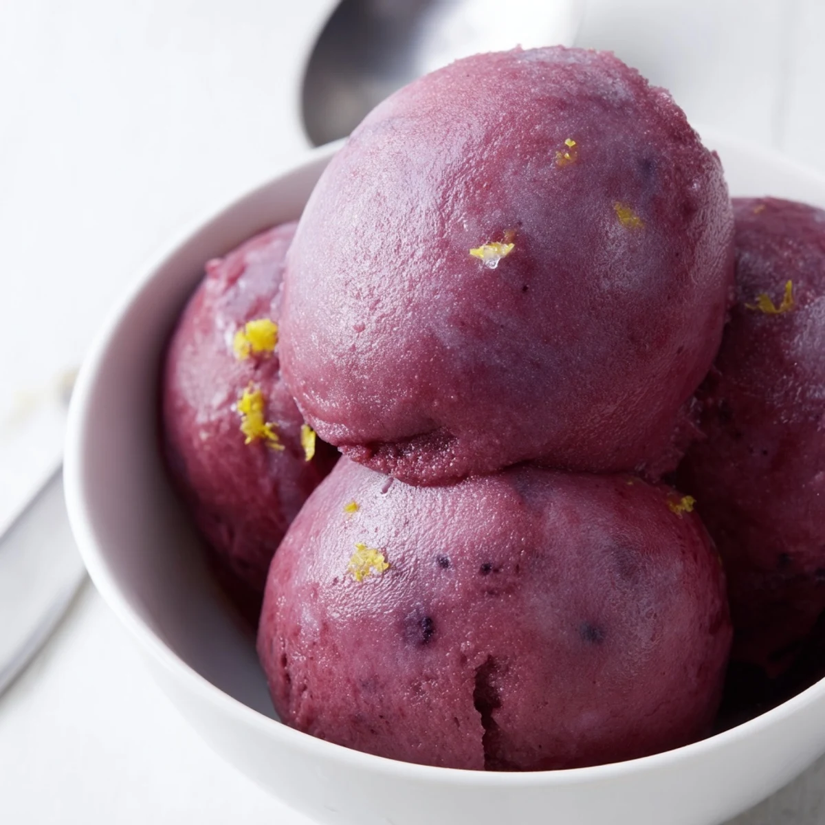 Vibrant purple no churn blueberry lemon sorbet scooped into a chilled glass bowl with fresh mint garnish