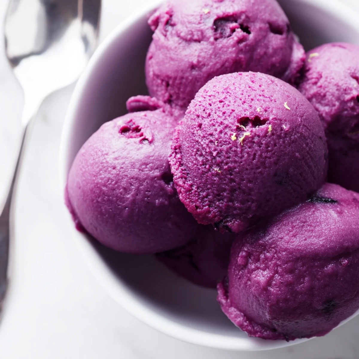 Bright mag scoops of refreshing no churn blueberry lemon sorbet served with fresh blueberries and lemon zest