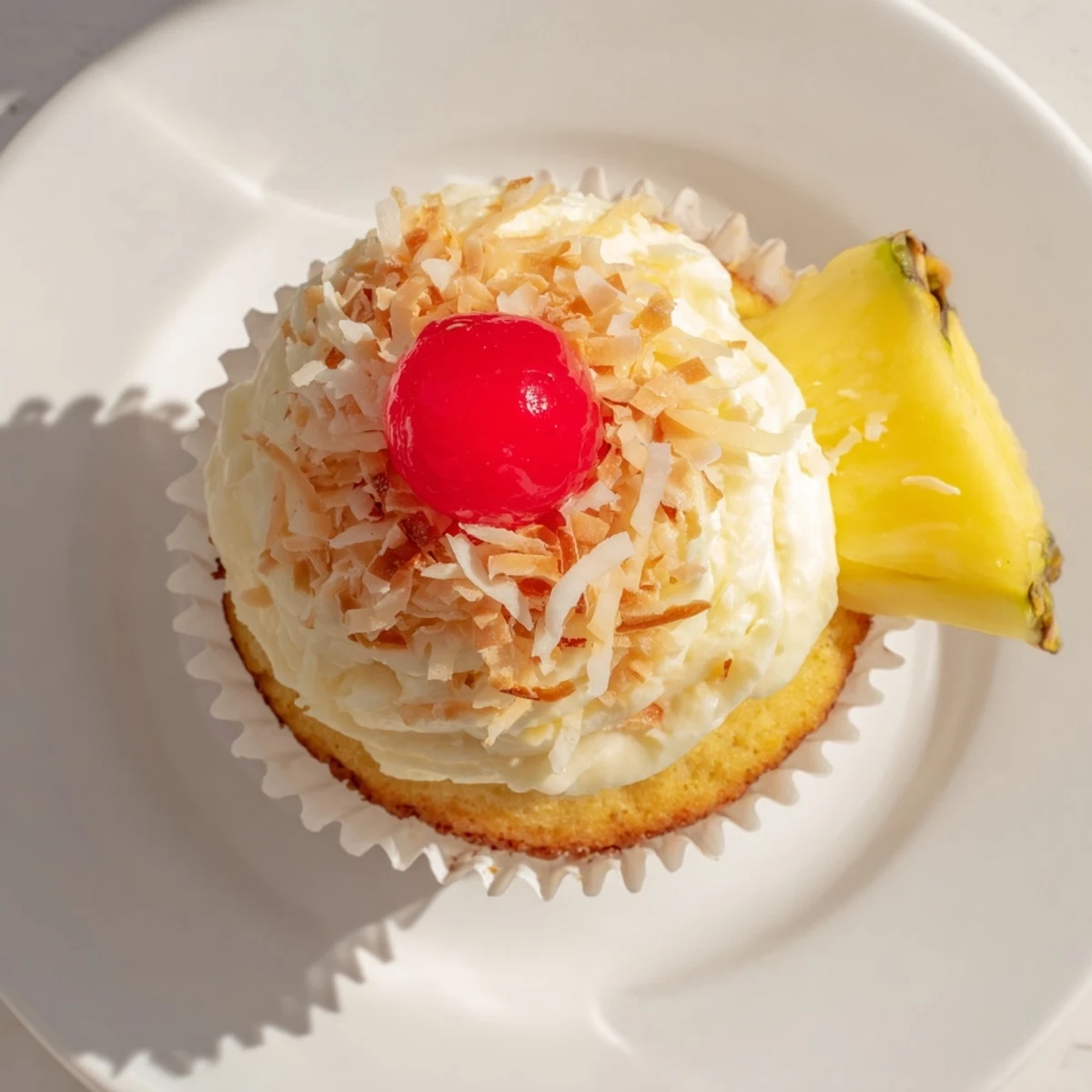 Festive Pina Colada cupcakes with rum-infused sponge cake topped with sweet coconut frosting and pineapple wedges