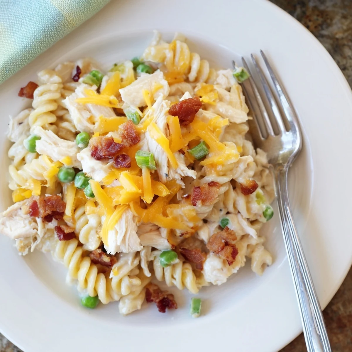 Spoonful of cheesy ranch chicken pasta casserole garnished with green onions and bacon bits