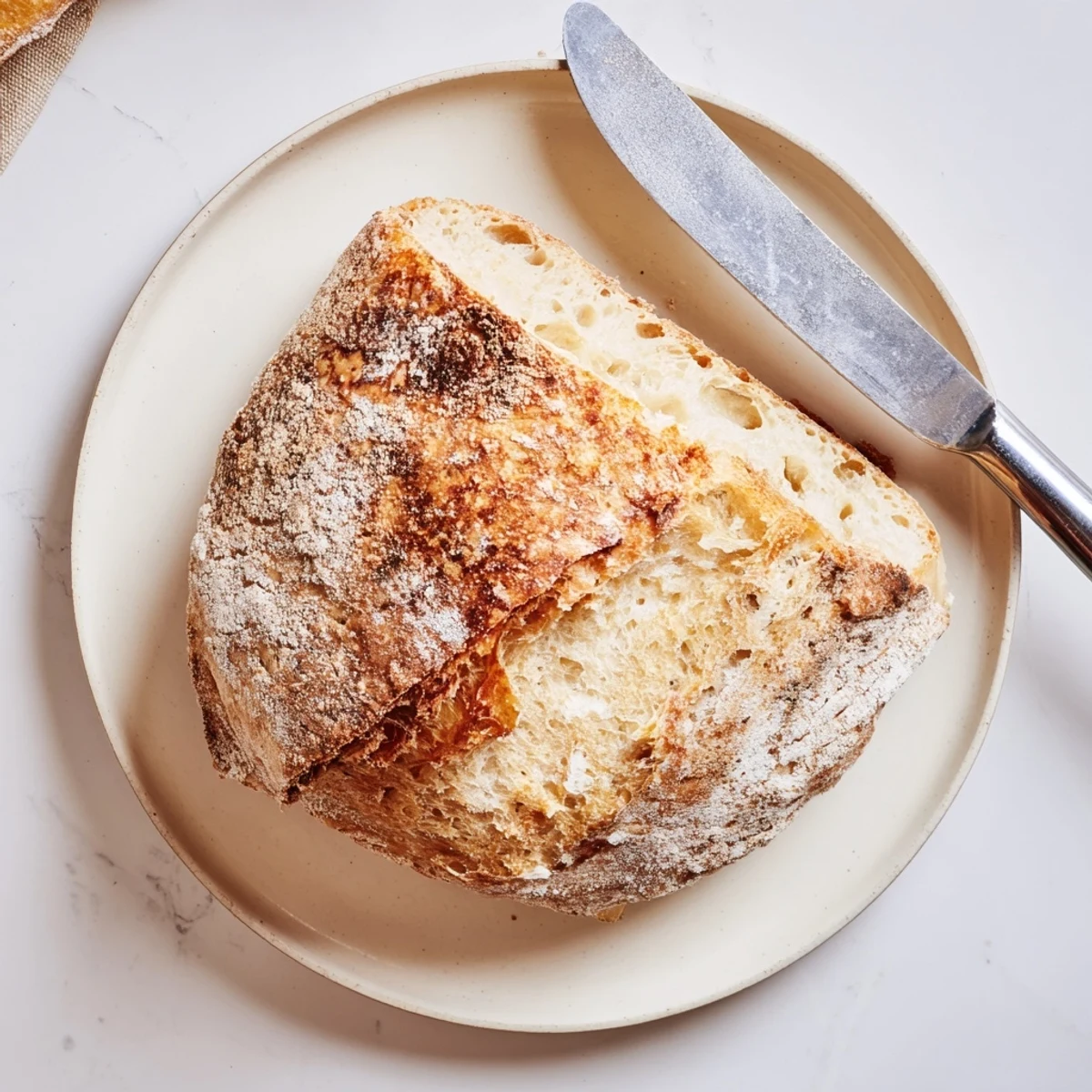 Golden brown sourdough bread loaf with crisp crust and chewy interior, sliced on wooden board