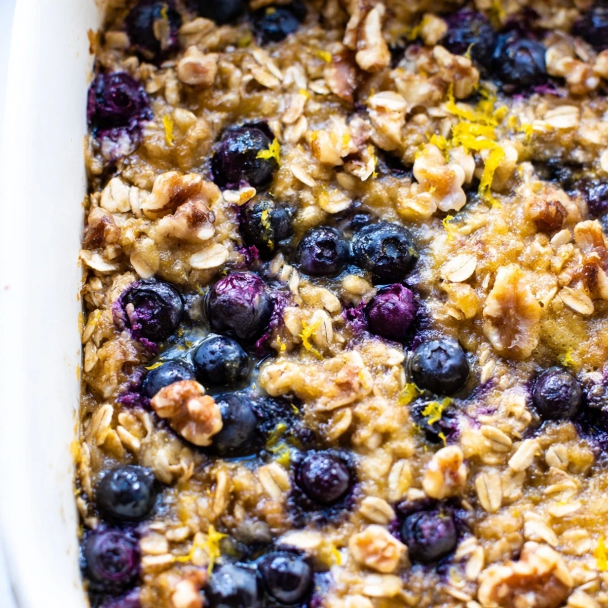 Wholesome baked oatmeal cups featuring plump blueberries and bright lemon zest on a rustic surface