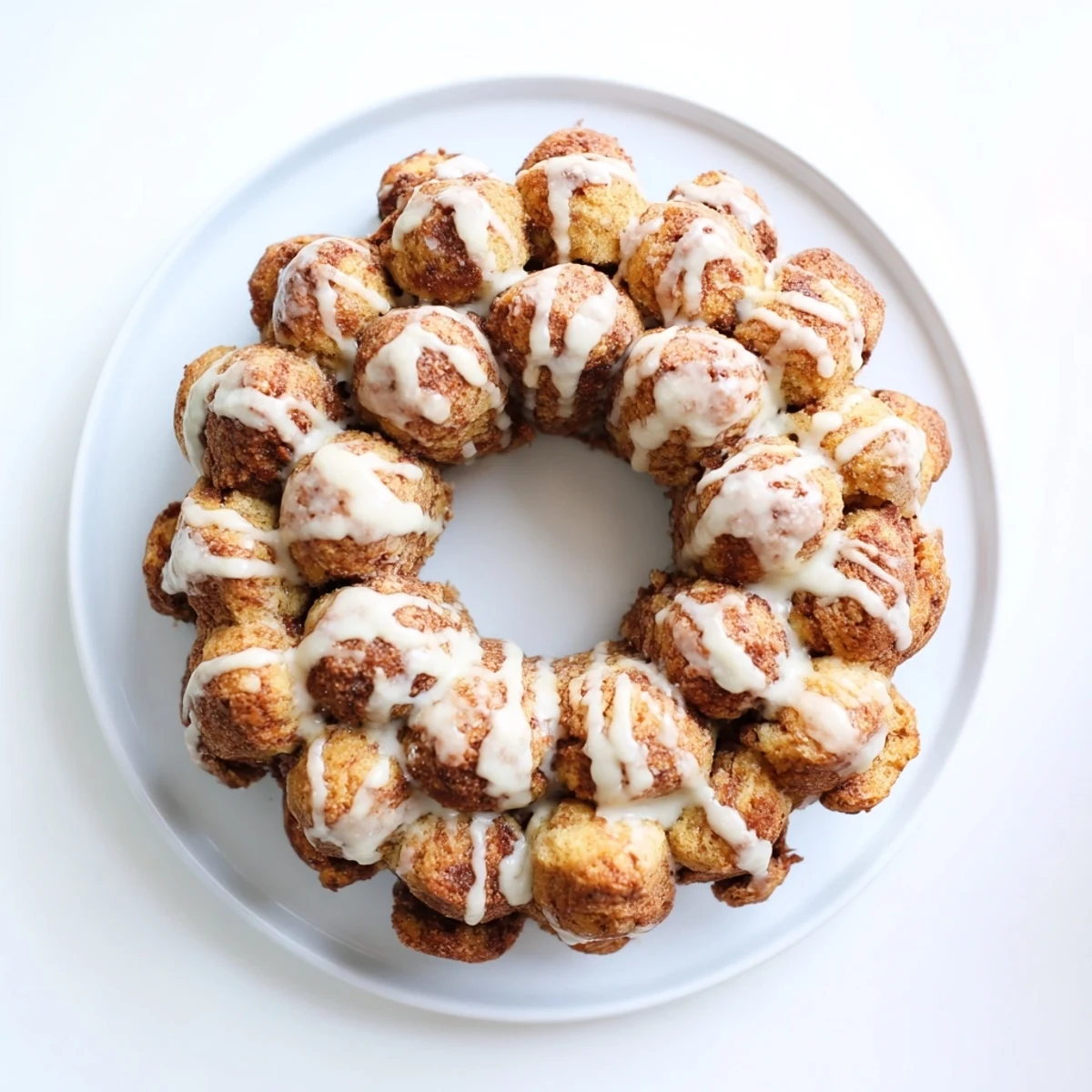 Pull-apart high protein no sugar monkey bread drizzled with vanilla glaze on serving plate