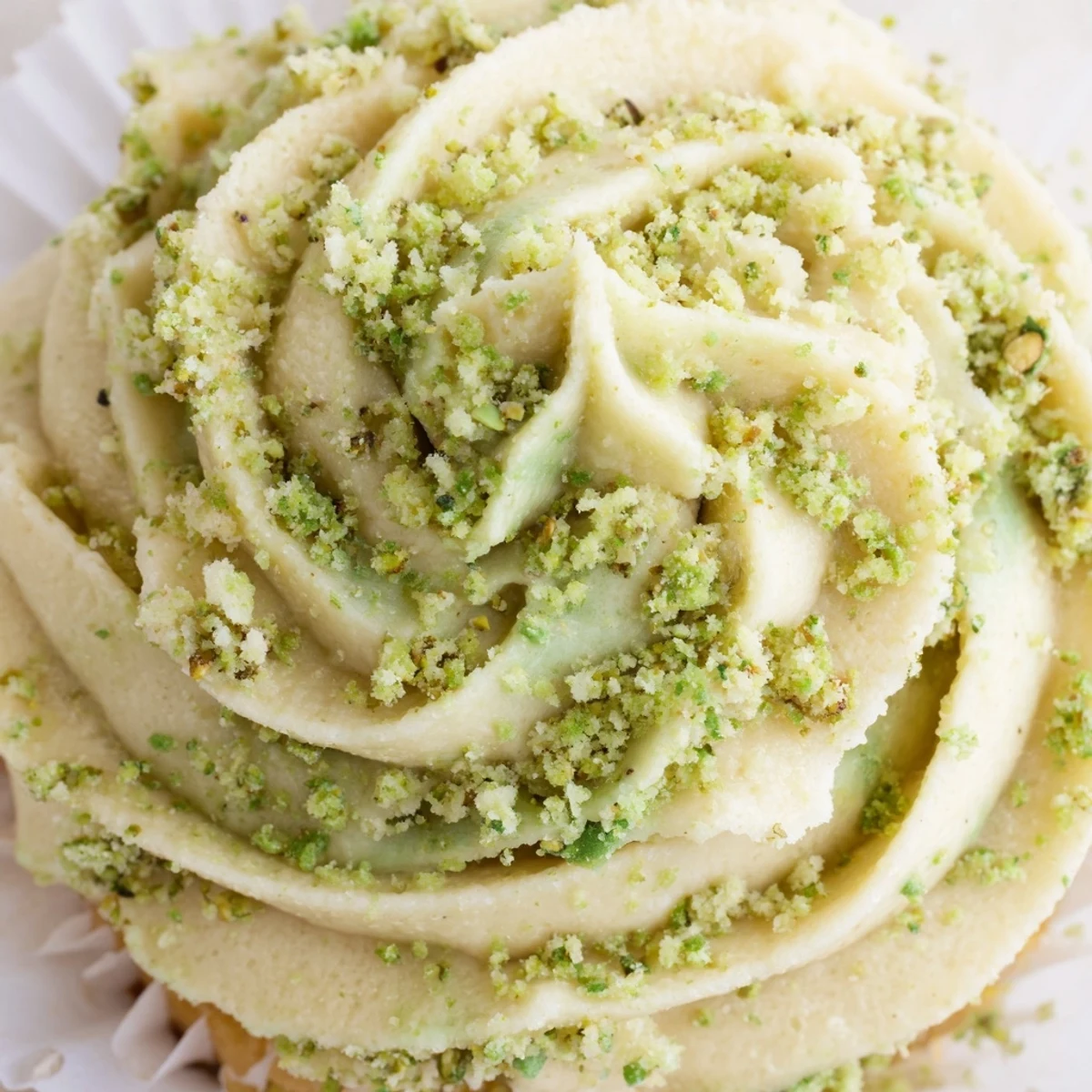 Soft pistachio cupcakes topped with creamy green buttercream and chopped nut garnish