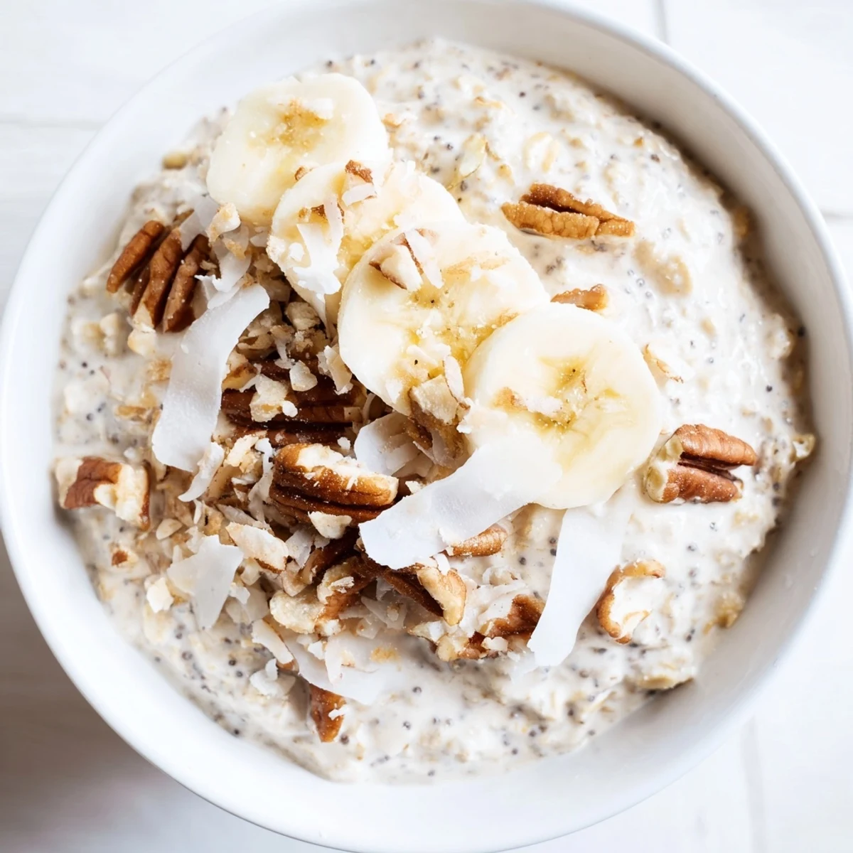 Coconut Cream Pie Overnight Oats served in a mason jar topped with toasted coconut flakes