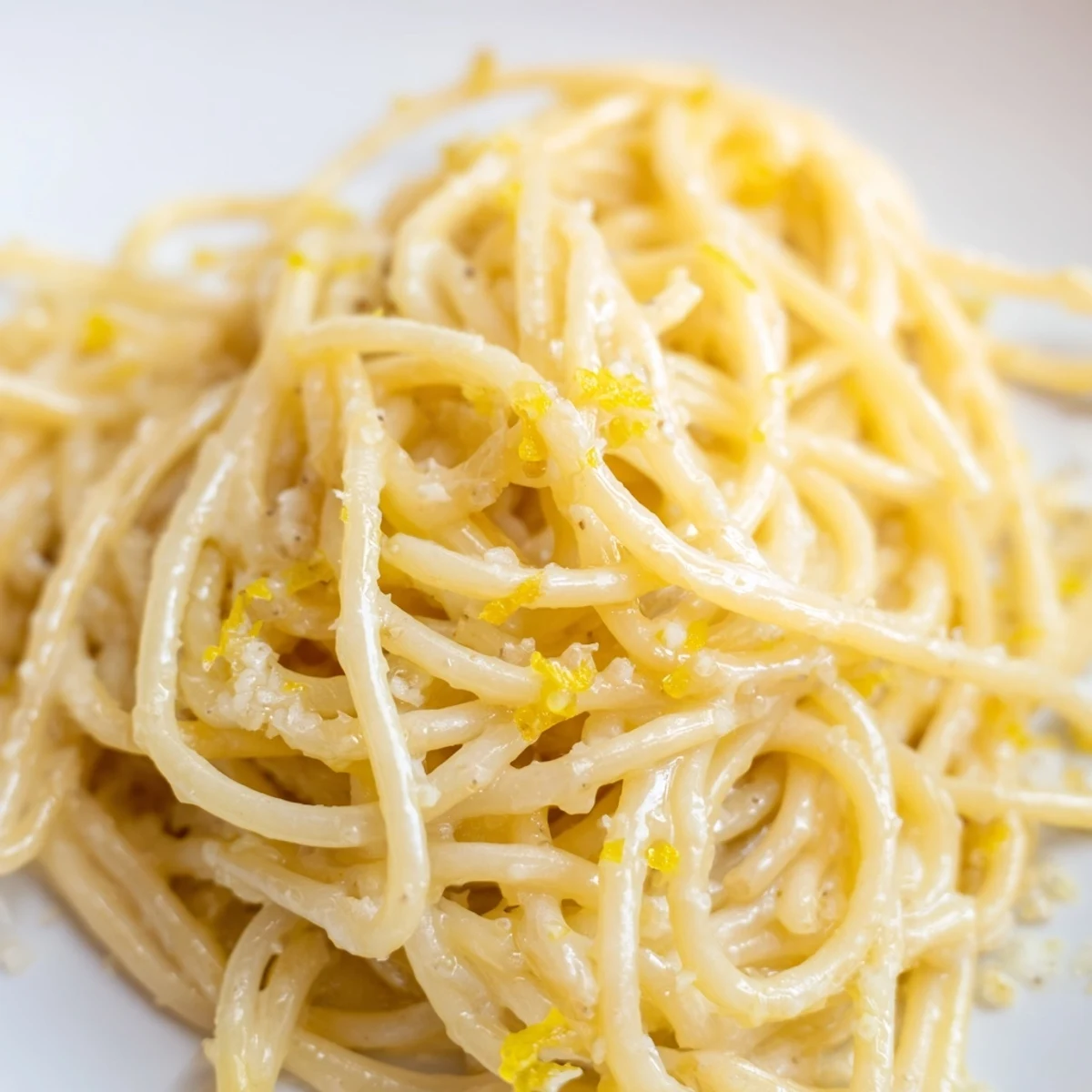Golden spaghetti coated in zesty Parmesan lemon sauce served in a rustic white bowl