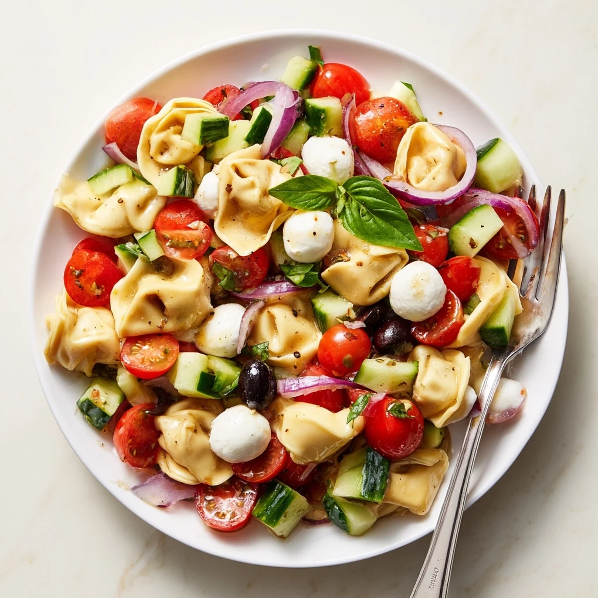 Colorful tortellini salad with cherry tomatoes, cucumber, and mozzarella in Italian dressing