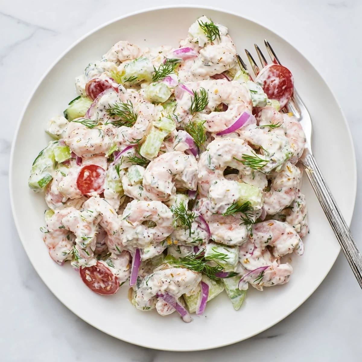 Plump shrimp salad recipe in a bowl topped with fresh dill and cucumber