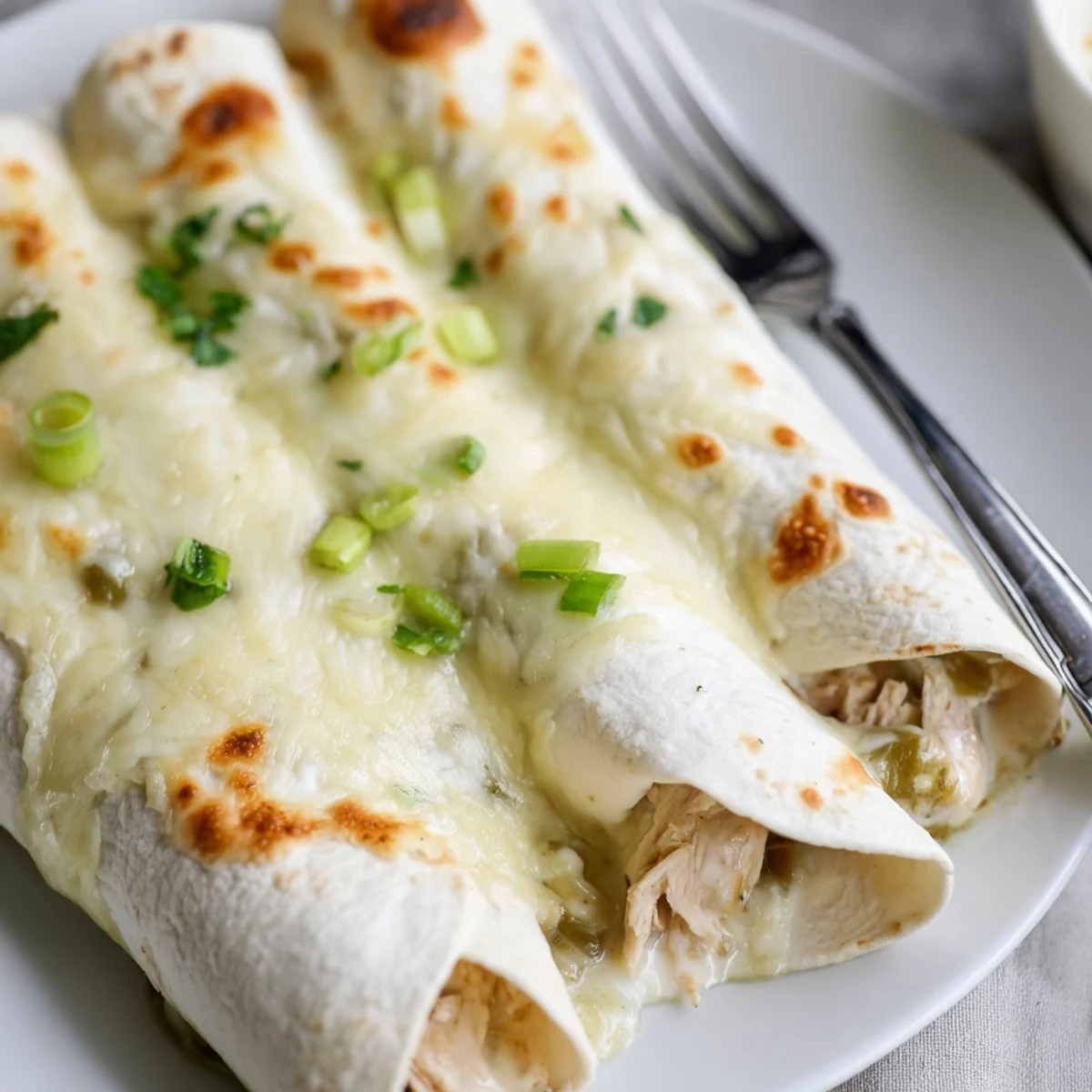 Hot Creamy White Chicken Enchiladas with velvety sauce, ready for family dinner