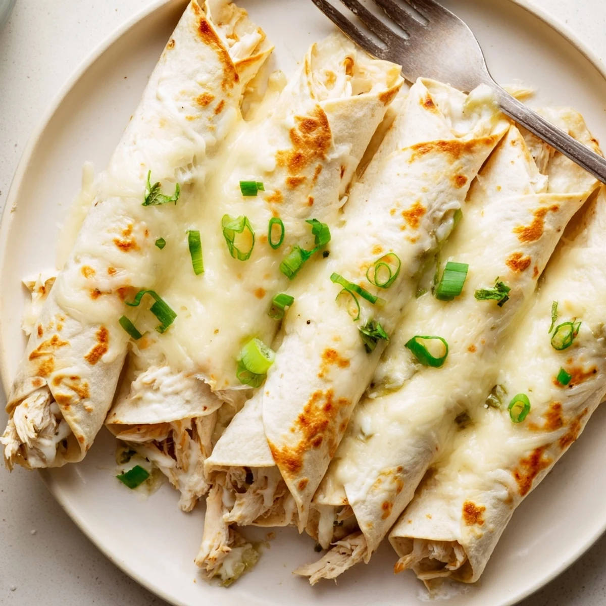 A slice of Creamy White Chicken Enchiladas plated with cilantro and lime wedge