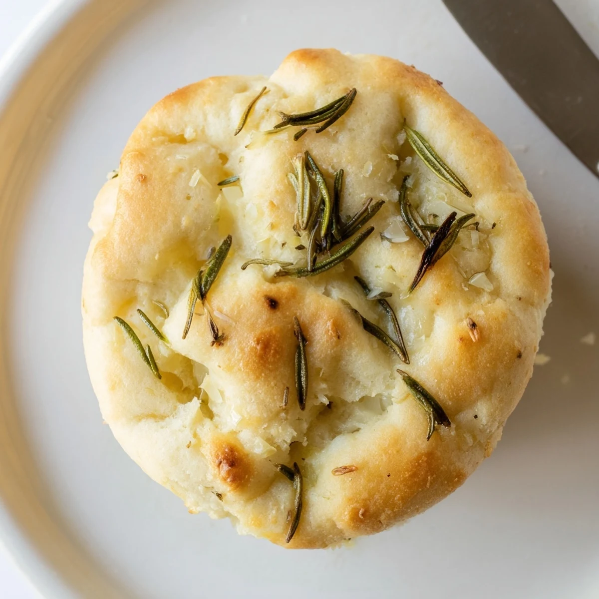 Golden Garlic Rosemary Focaccia Muffins topped with fresh sprigs and olive oil