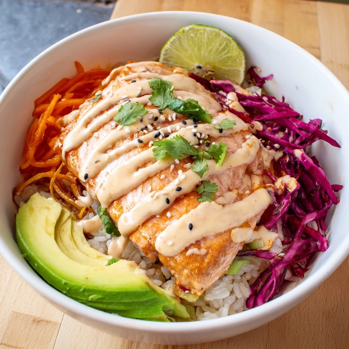 Oven-roasted Bang Bang Salmon Bowls Recipe plated with shredded cabbage, sesame, lime