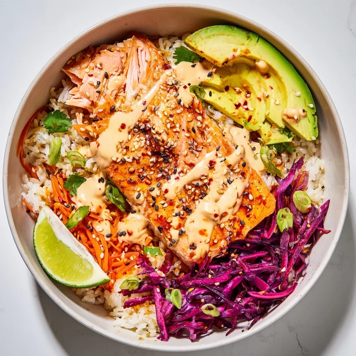 Drizzled creamy sriracha sauce atop salmon, avocado, rice in Bang Bang Salmon Bowls Recipe