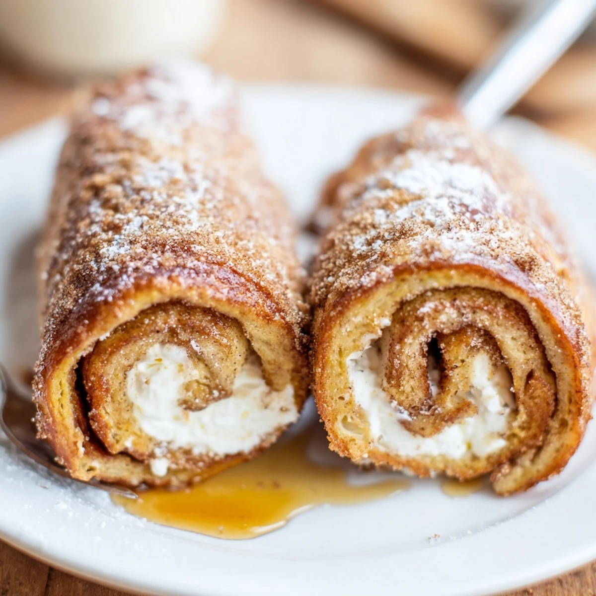 Golden-browned Cinnamon Roll French Toast Roll Ups dusted with cinnamon-sugar, served warm.