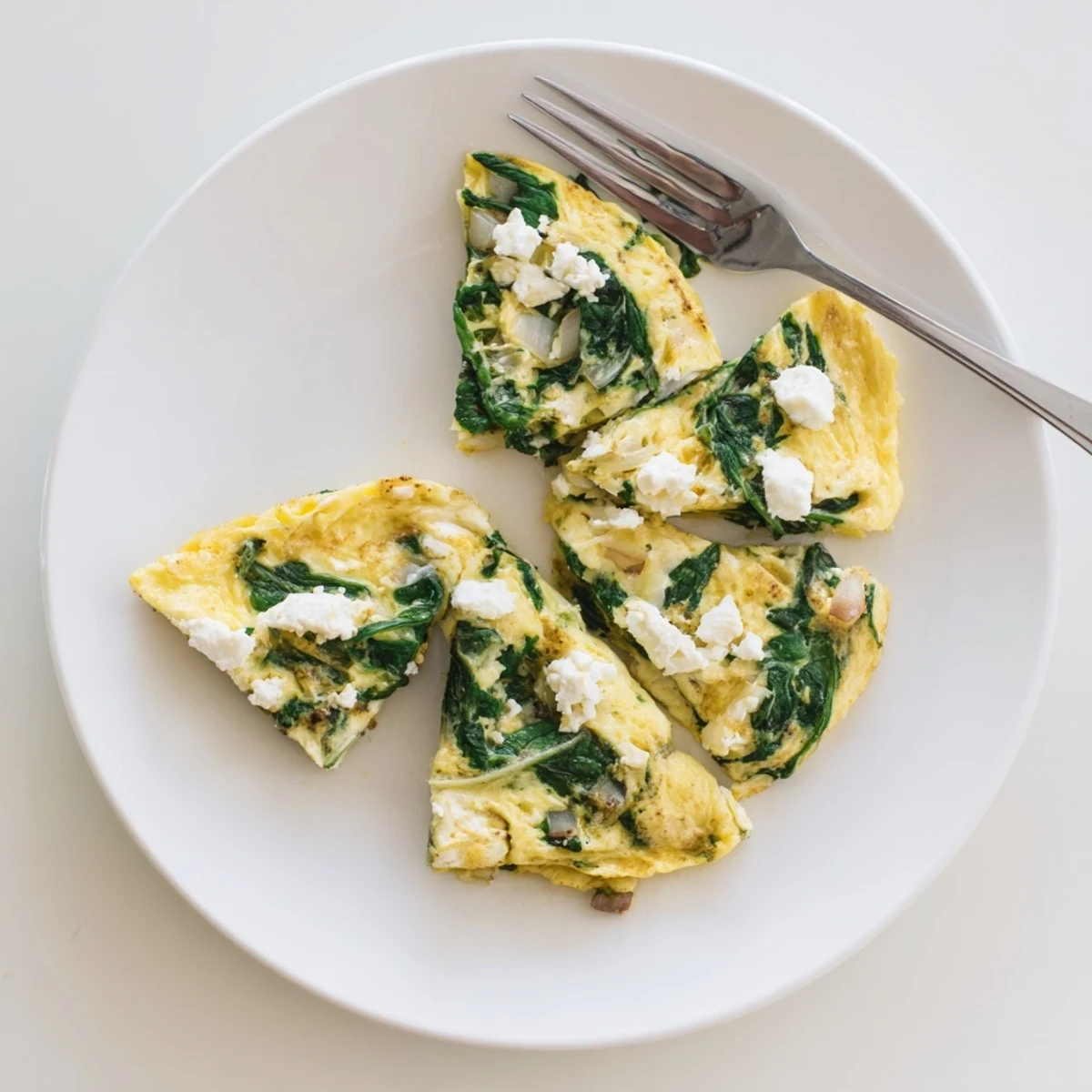 Fluffy Mediterranean spinach feta omelet recipe plated with fresh herbs and sunny-side presentation