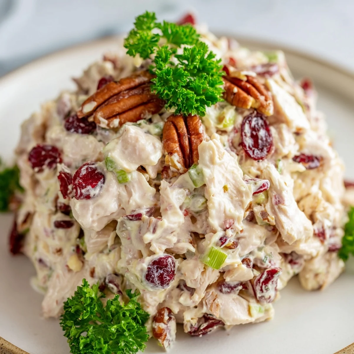 Creamy cranberry pecan chicken salad plated over fresh mixed greens with tender diced chicken chunks