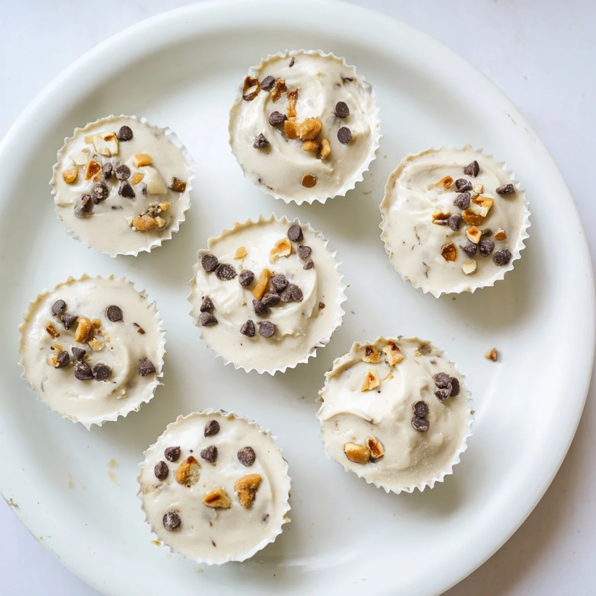 Frozen peanut butter Greek yogurt bites arranged in a muffin tin with chocolate chip toppings