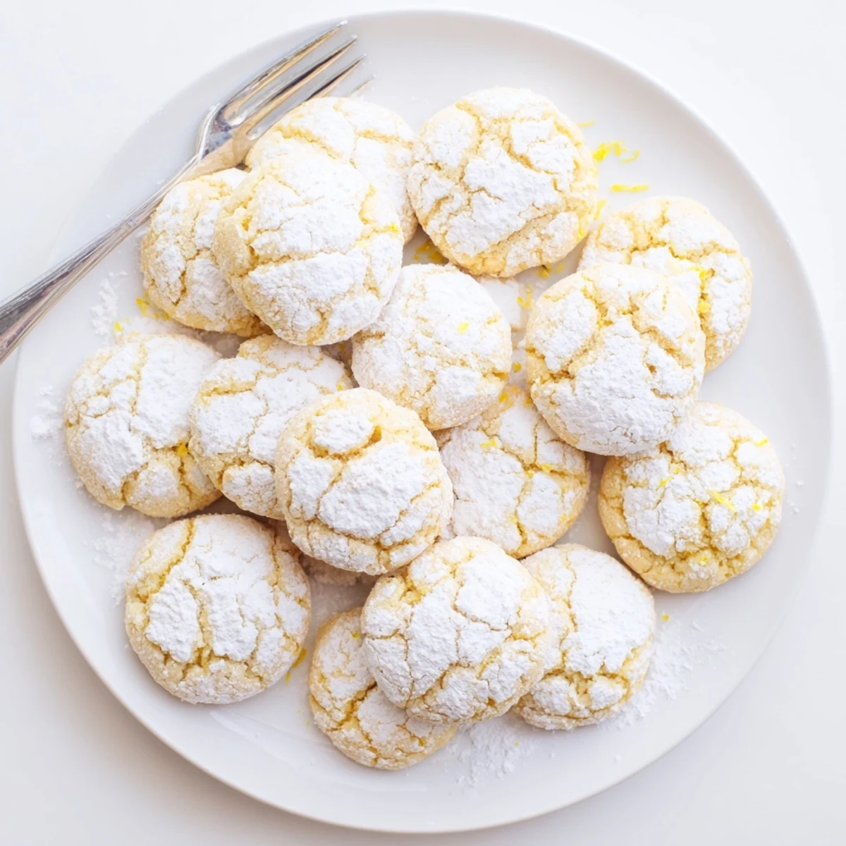 Freshly baked lemon pixie cookies dusted with white powdered sugar on a cooling rack