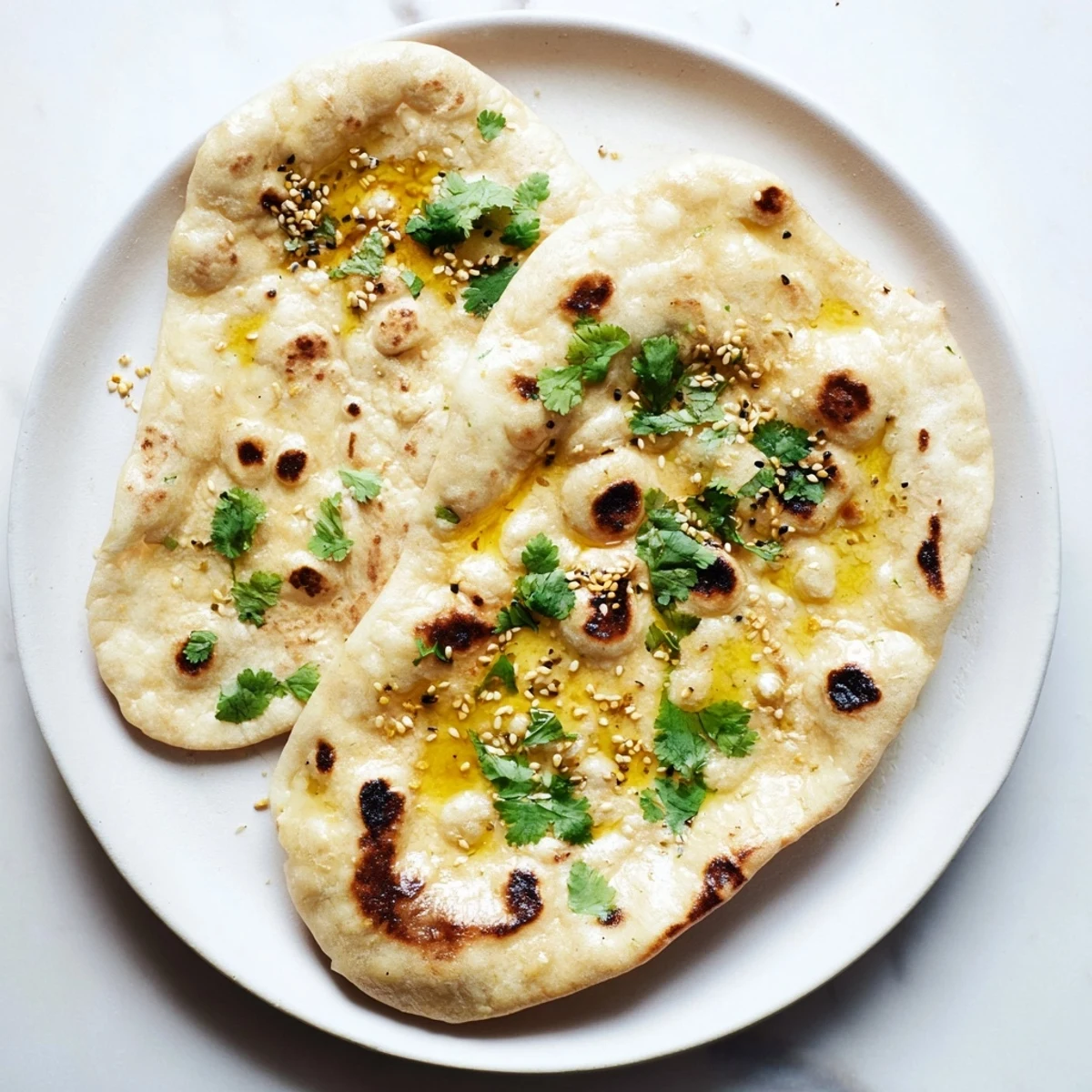 Golden brown sourdough discard naan brushed with melted butter and fresh herbs