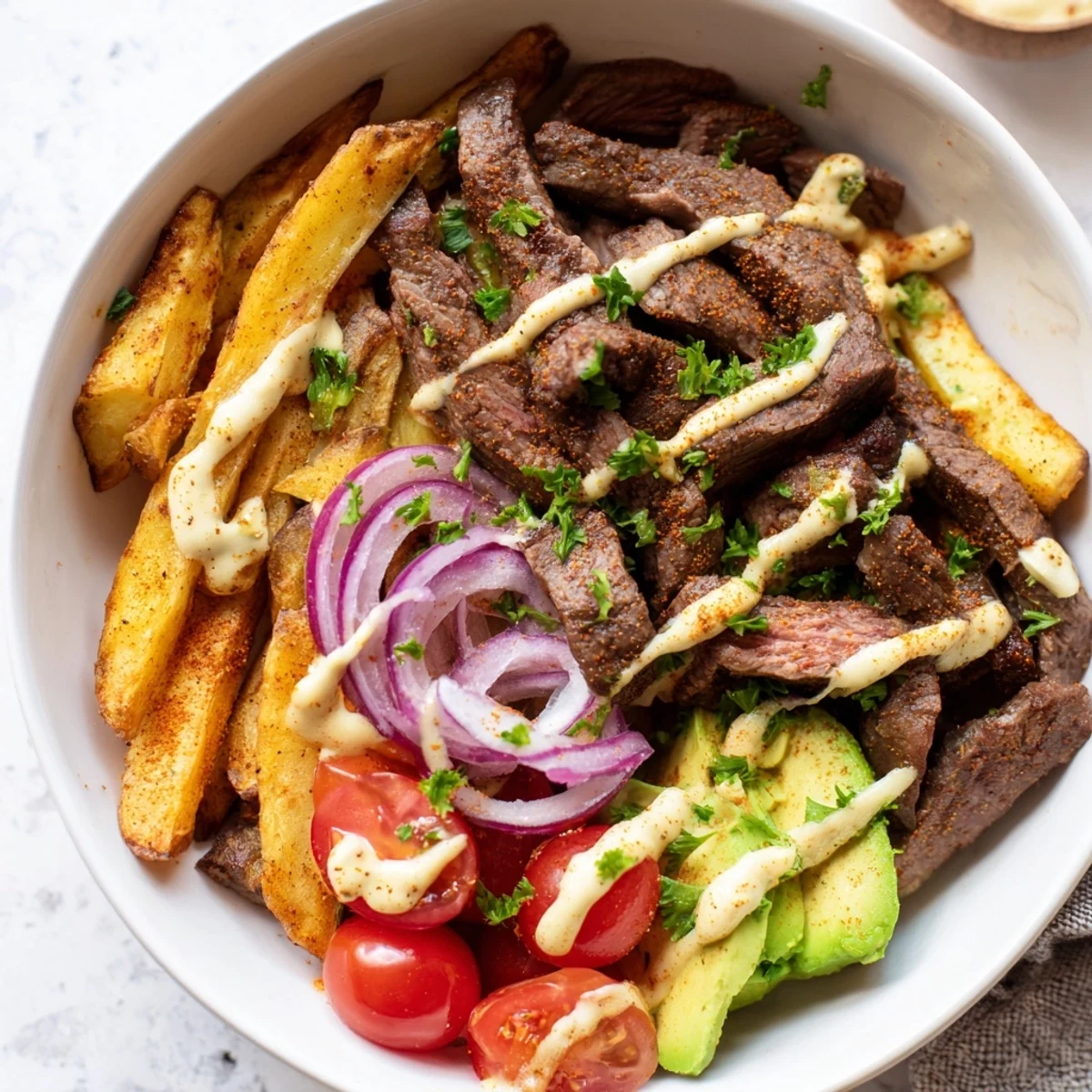 Hearty serving bowl featuring perfectly seared steak strips, smoky baked fries, and crisp vegetables.