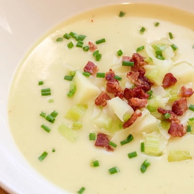 Velvety Creamy Potato and Leek Soup with Turkey Bacon served steaming hot in a rustic bowl.