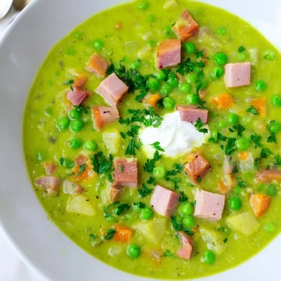 Steaming Spring Pea Soup with Ham and Turkey served alongside a slice of rustic crusty bread for dipping.  
