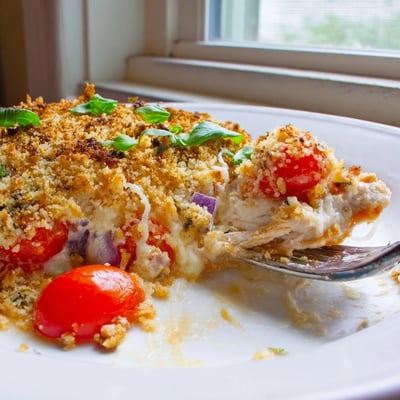 Juicy chicken bruschetta casserole topped with crispy breadcrumbs melted cheese and fresh basil